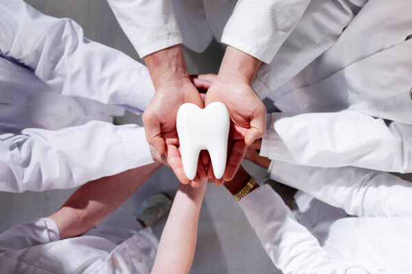 Group Of Dentists Holding Tooth. Dental Teeth Whitening